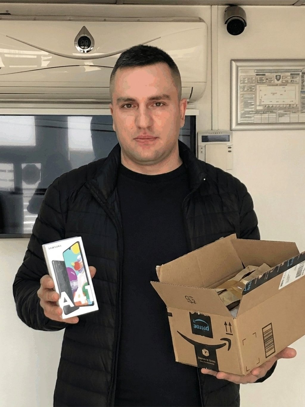 Cliente segurando a caixa aberta e um celular lacrado que veio dentro